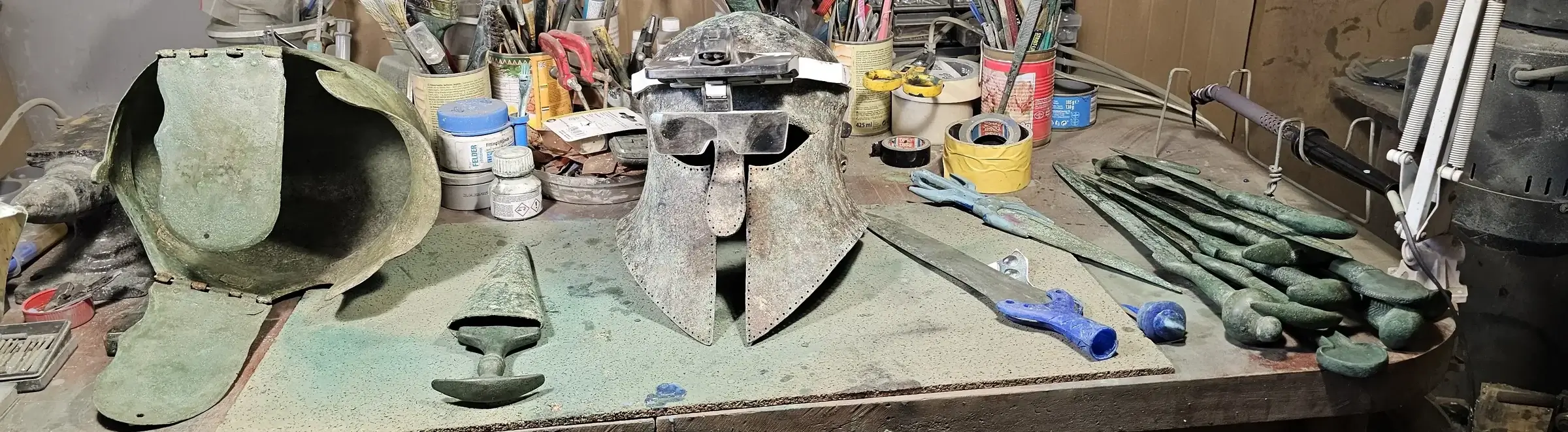 Conservator’s workbench with ancient bronze helmets and arms during conservation