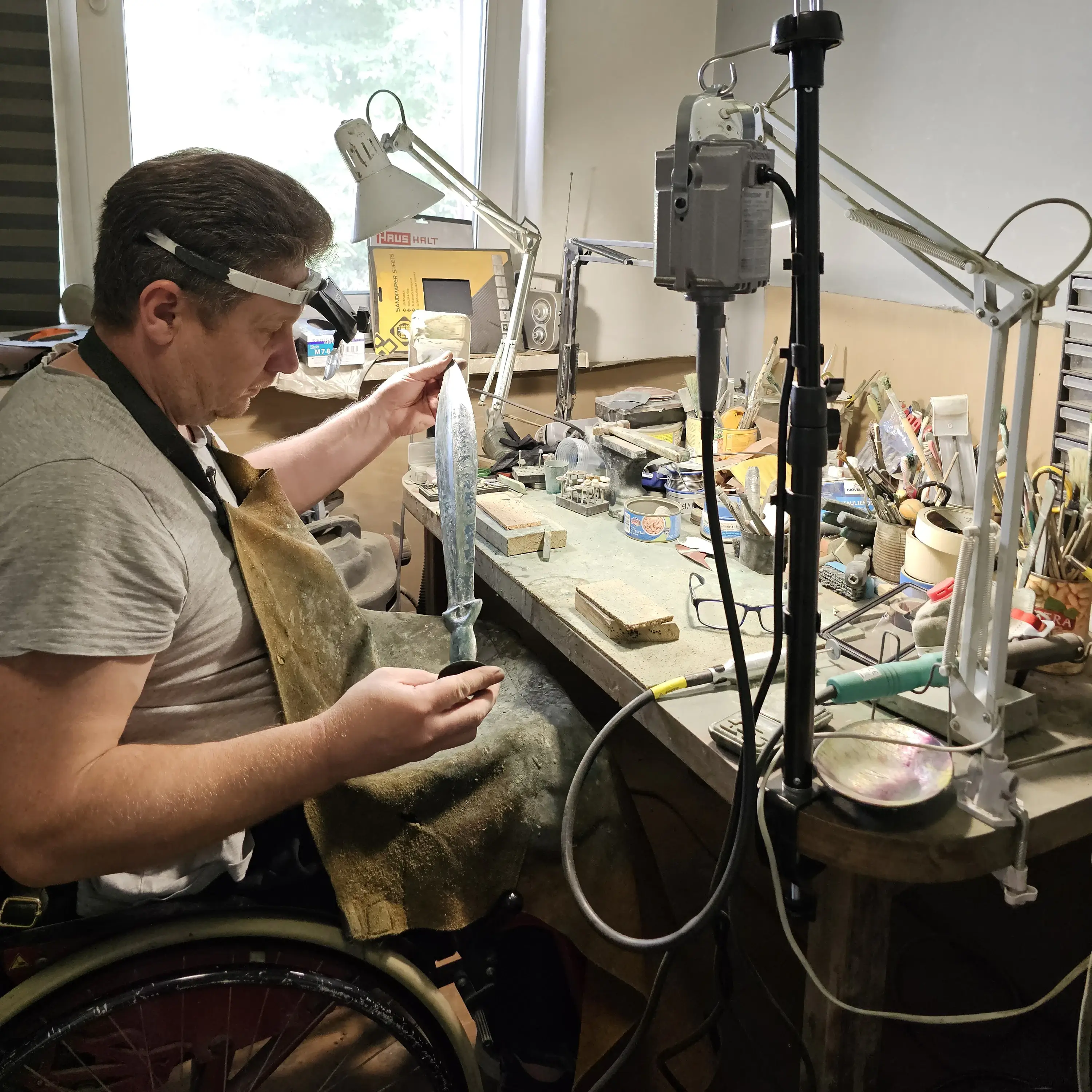 Volodymyr Marchenko examining an ancient bronze sword in the workshop